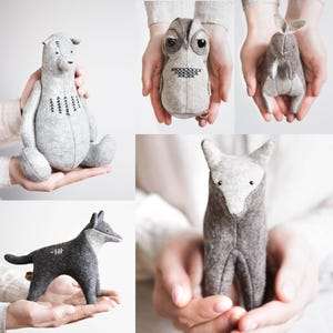 Può includere: Quattro giocattoli di animali in feltro fatti a mano: un orso grigio con alberi ricamati, un gufo grigio con occhi neri, un coniglio grigio con orecchie lunghe e un lupo grigio con il naso nero.
