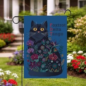 May include: A white ceramic mug with a black handle and the text "But First, Coffee" in a bold, black font. The mug is set against a blurred background, suggesting a cozy setting.