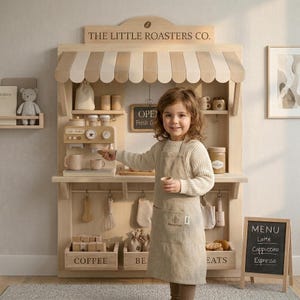 May include: A wooden play cafe with a striped awning, labeled "THE LITTLE ROASTERS CO.". It features a coffee maker, menu, and a child wearing an apron. The menu lists "Latte, Cappuccino, Espresso".