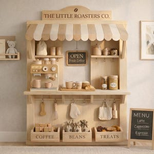 May include: A wooden play coffee shop with a striped awning, shelves, and accessories. The sign reads "THE LITTLE ROASTERS CO." and "OPEN Fresh Coffee." Includes a menu board with "Latte, Cappuccino, Espresso."