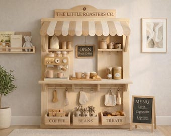 Könnte beinhalten: Ein Spielzeug-Kaffeehaus aus Holz mit gestreifter Markise, Regalen und Zubehör. Das Schild lautet "THE LITTLE ROASTERS CO." und "OPEN Fresh Coffee". Enthält eine Menütafel mit "Latte, Cappuccino, Espresso."