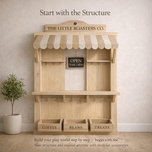 May include: Wooden play structure with a striped awning, hooks, and three labeled bins: "COFFEE," "BEANS," and "TREATS." A small chalkboard sign reads "OPEN Fresh Coffee." The text "THE LITTLE ROASTERS CO." is above the awning.