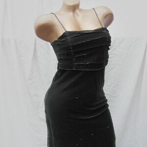 May include: A black sleeveless dress featuring thin spaghetti straps and a straight neckline. The bodice is detailed with horizontal fabric pleats across the chest, while the skirt falls in a straight, fitted silhouette made of a dark fabric.