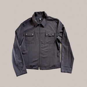 Könnte beinhalten: Eine dunkelgraue Reißverschlussjacke mit zwei großen Pattentaschen und einem kleinen Etikett mit der Aufschrift "A.J. MORR.