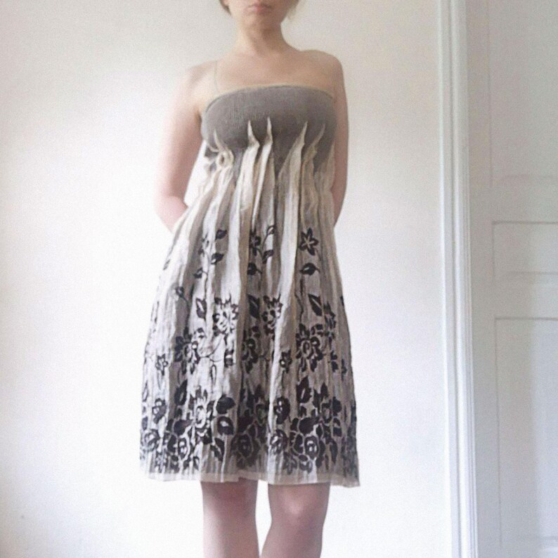 May include: A strapless dress with a beige skirt and a gray bodice. The skirt features a black floral pattern. The dress is knee-length and appears to be made of a lightweight fabric, suitable for warm weather.