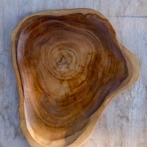 May include: A large, wooden serving bowl with a natural, brown finish. The bowl is made from a single piece of wood and has a unique, organic shape.
