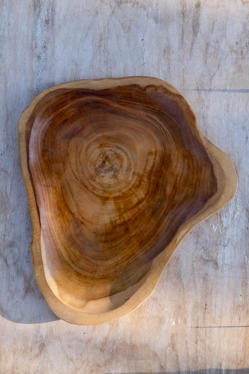 May include: A large, wooden serving bowl with a natural, brown finish. The bowl is made from a single piece of wood and has a unique, organic shape.