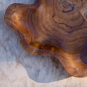 May include: A large, natural wood serving tray with a unique, organic shape. The tray is made of dark brown wood with a rich grain pattern.