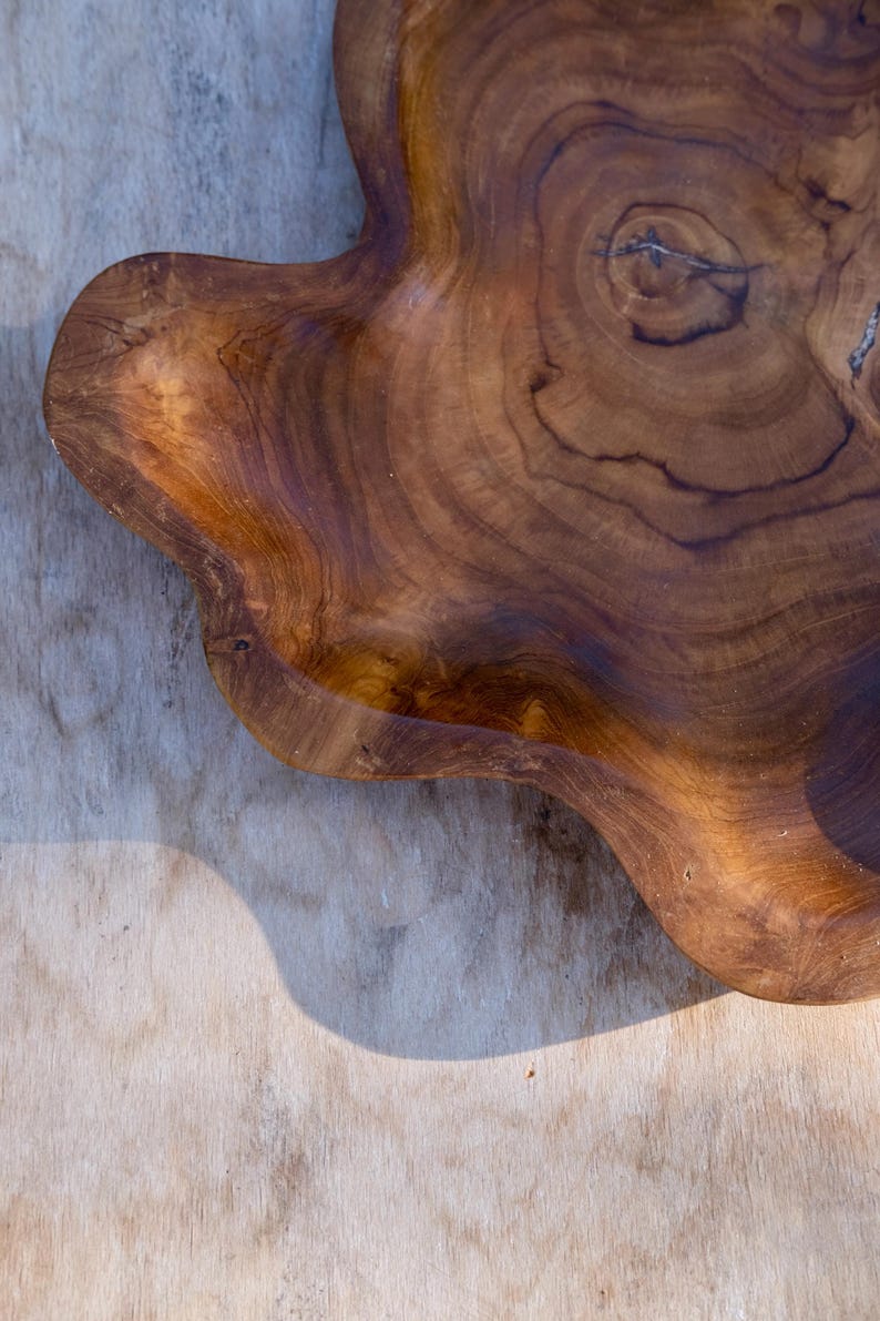 May include: A large, natural wood serving tray with a unique, organic shape. The tray is made of dark brown wood with a rich grain pattern.