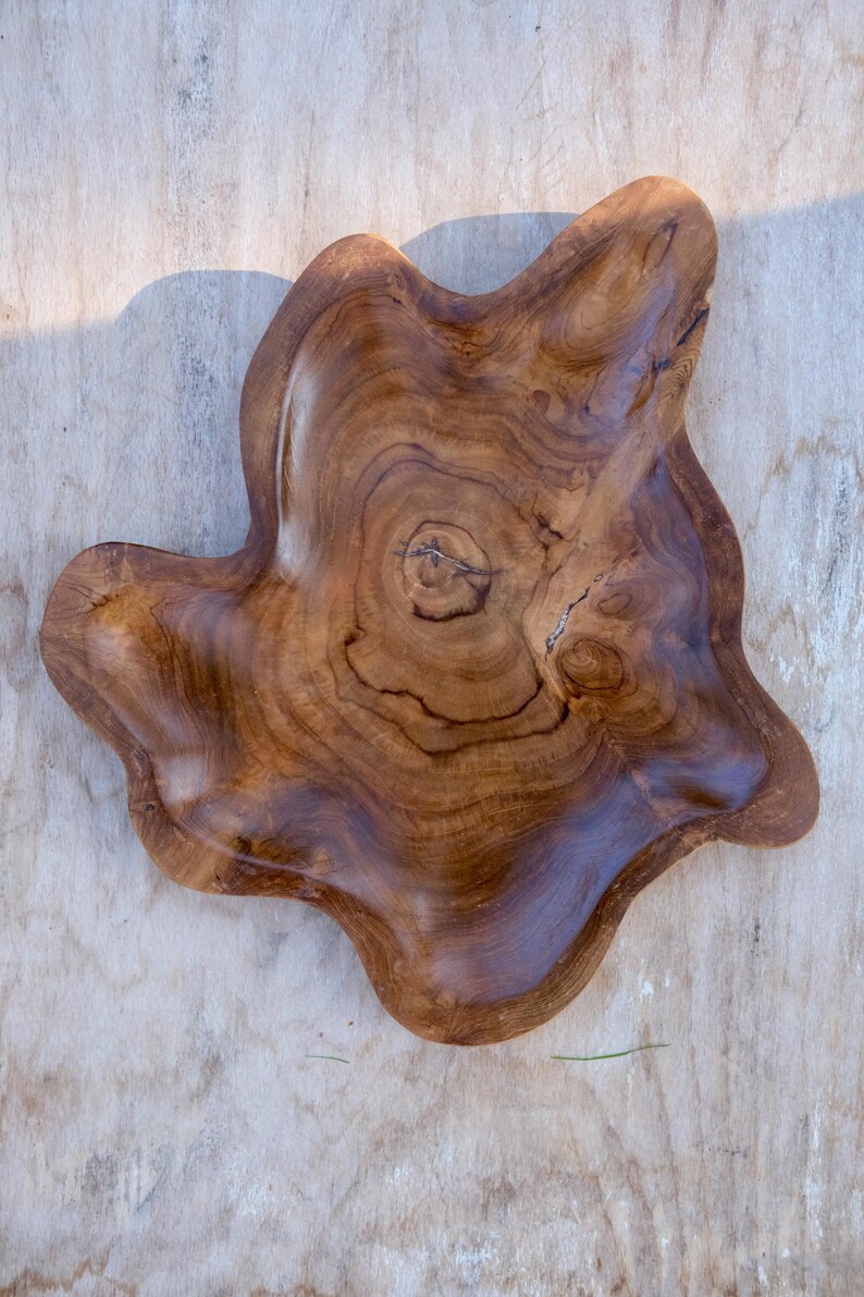 May include: A large, natural wood serving bowl with a unique, irregular shape. The bowl is made of dark brown wood with a natural grain pattern.