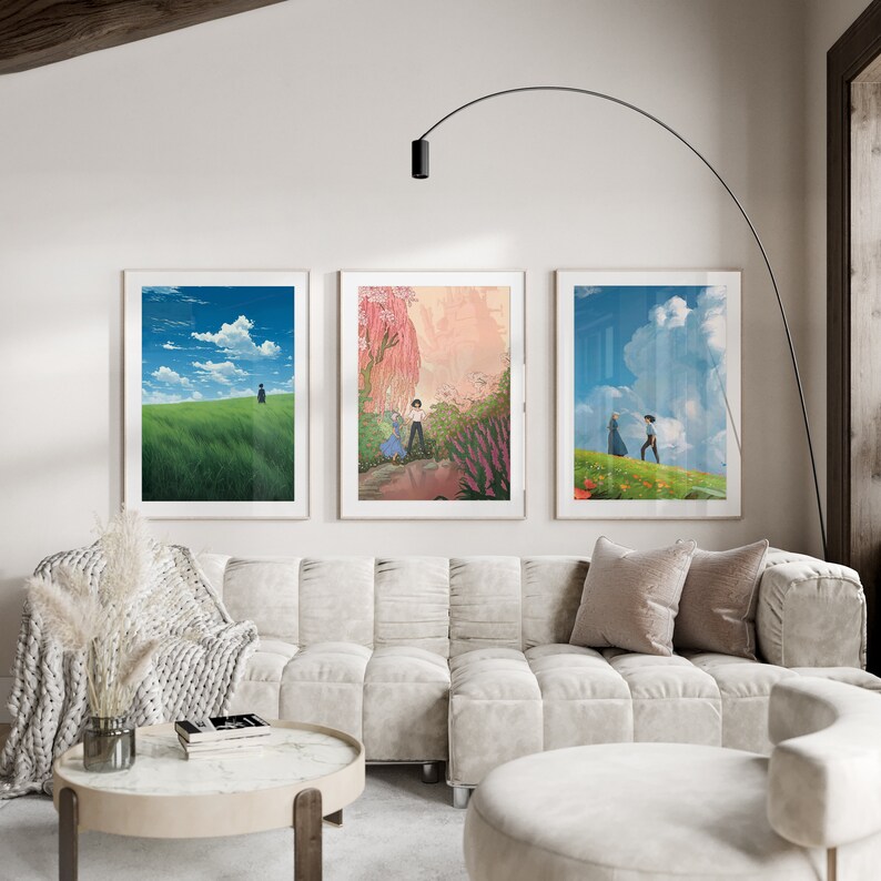 May include: Three framed prints of anime-style landscapes with a couple walking in a field, a woman standing in a field, and a couple walking in a forest. The prints are hanging on a white wall above a white couch.