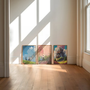 May include: Three framed art prints on a wooden floor. The prints feature colorful landscapes with a whimsical castle, a couple walking in a field, and a pink and green forest.