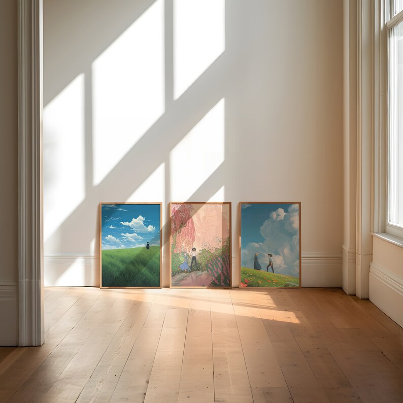 May include: Three framed prints of anime-style artwork depicting landscapes with figures walking in the distance. The prints are hung on a white wall in a room with wooden floors.