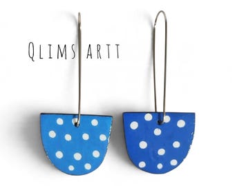 May include: A pair of blue semi-circular drop earrings featuring white polka dots and silver-toned wire hooks. The text QLIMS ARTT is printed in black above the earrings. The design consists of two matching blue shapes with white dots.