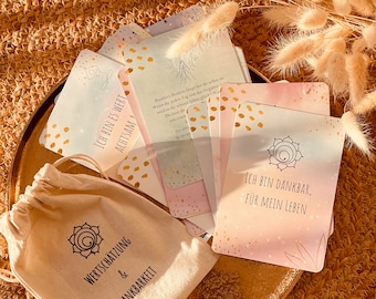 May include: A set of affirmation cards with gold accents and text, including "I AM WORTHY" and "I AM GRATEFUL FOR MY LIFE." The cards are displayed on a gold tray with a small canvas bag that reads "APPRECIATION & GRATITUDE."