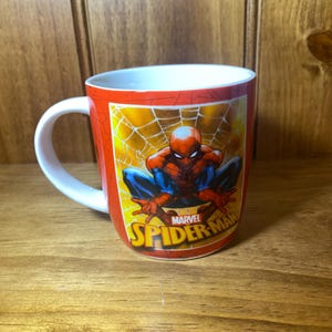 Puede incluir: Taza de cer&aacute;mica roja con Spider-Man sobre un fondo de telara&ntilde;a amarilla. La taza tiene un asa blanca y el logotipo de Marvel Spider-Man. Un art&iacute;culo divertido para los fan&aacute;ticos del superh&eacute;roe. Ideal para bebidas calientes.