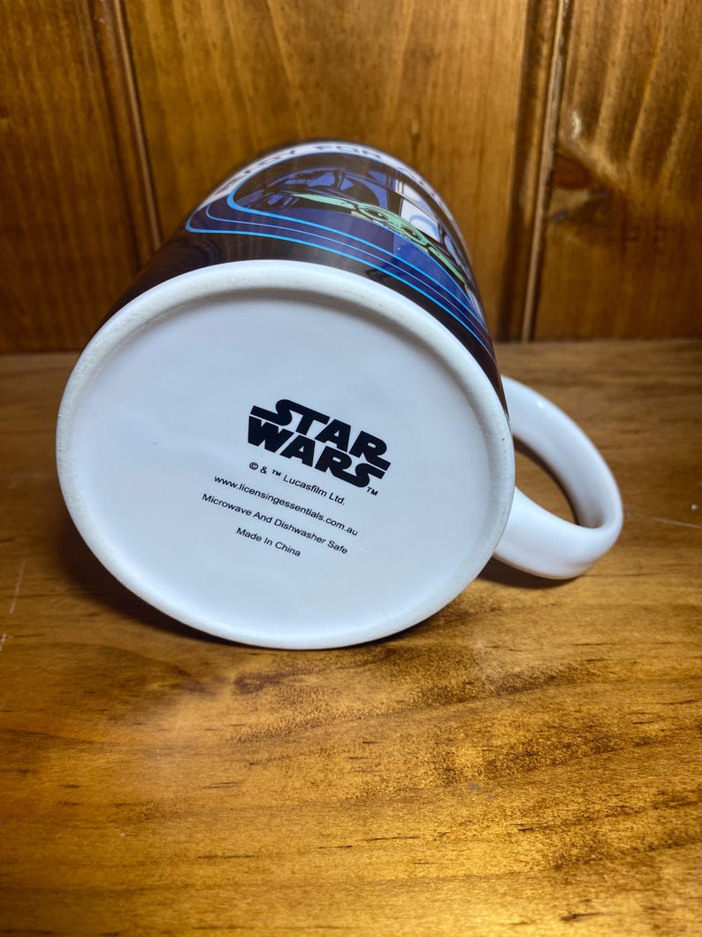 K&ouml;nnte beinhalten: Wei&szlig;e Star Wars-Keramiktasse mit einem schwarzen und blauen Design. Die Tasse tr&auml;gt das Star Wars-Logo und ist mikrowellen- und sp&uuml;lmaschinenfest.