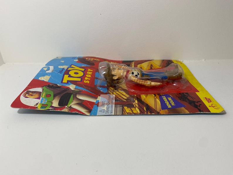 以下が含まれることがあります： ディズニーピクサーの映画トイストーリーのウッディのプラスチック製アクションフィギュアです。ウッディは、トレードマークのテンガロンハット、ベスト、ジーンズを着用しています。フィギュアは曲げることができ、ウッディとバズ・ライトイヤーの画像が描かれたカードにパッケージされています。
