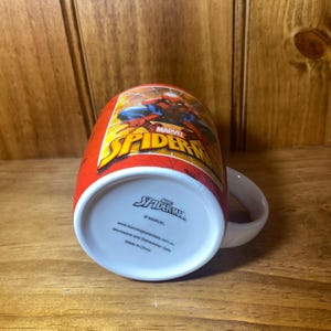 Puede incluir: Taza roja de cer&aacute;mica de Spider-Man con asa blanca. La taza presenta el logotipo de Spider-Man y un gr&aacute;fico de Spider-Man. La parte inferior de la taza tiene el logotipo de Spider-Man y el texto "Microwave and Dishwasher Safe".