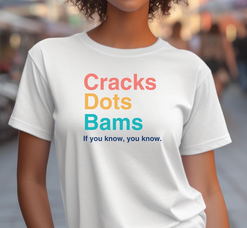 May include: White t-shirt with the text "Cracks Dots Bams" in rainbow colors and the phrase "If you know, you know." in blue.
