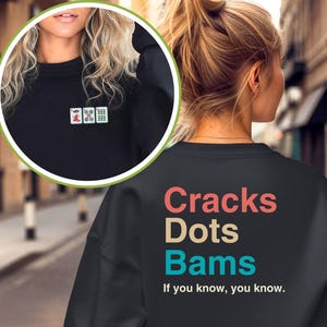 May include: Black sweatshirt with a colourful graphic that says "Cracks Dots Bams" and the text "If you know, you know."  The front of the sweatshirt has a small embroidered image of three mahjong tiles.