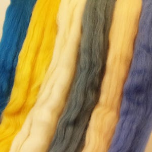 May include: Six strands of wool yarn in various colors, including blue, yellow, white, and light blue. The yarn is arranged in a row, with the ends of each strand overlapping.