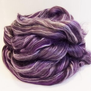 May include: A bundle of purple and white merino wool roving. The wool is soft and fluffy, and it is perfect for spinning or felting.