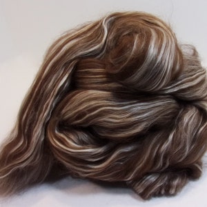 May include: Brown and white wool roving with a striated pattern. The roving is arranged in a loose, fluffy pile.