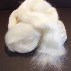 May include: A large amount of white wool roving, a type of fiber used for spinning yarn or felting.