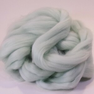 May include: A large bundle of light green wool roving. The wool is soft and fluffy, and it is perfect for felting, spinning, or other fiber crafts.