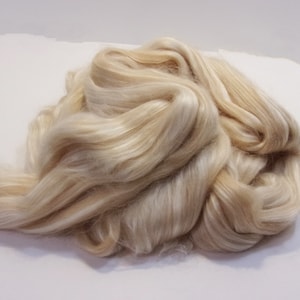 May include: A pile of soft, white, and cream-colored silk fibers. The fibers are long and silky, and they are arranged in a loose, flowing pile.