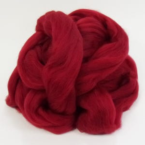 May include: A large pile of red wool roving. The wool is soft and fluffy, and it is perfect for felting or spinning.