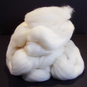 May include: A large pile of white wool roving, a fluffy and soft material used for spinning yarn or felting.