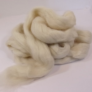 May include: A large pile of white wool roving. The wool is soft and fluffy, and it is perfect for felting or spinning.