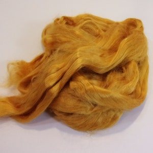 May include: A pile of golden yellow silk fiber. The fiber is soft and fluffy, and it is perfect for spinning or felting.