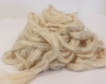 May include: A pile of off-white raw silk fibers. The fibers are long and soft, and they are perfect for spinning or weaving.