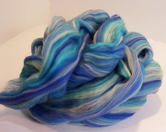 May include: A bundle of blue, white, and purple wool roving. The roving is arranged in a loose, swirling pattern.