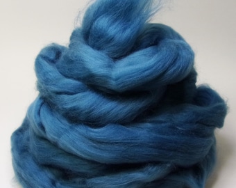 May include: A pile of vibrant blue wool roving, ideal for fiber art projects. The wool is a deep, saturated shade of blue, with a soft, fluffy texture. The fibers are loosely arranged, creating a visually appealing and tactile experience.