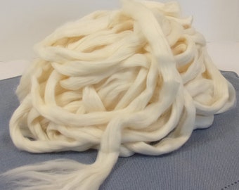 May include: A large pile of white cotton fiber, resembling a fluffy cloud. The cotton is loose and unspun, ready for spinning or other crafting projects.