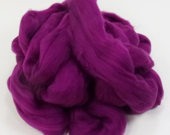 May include: A pile of vibrant, deep magenta-colored wool roving. The wool fibers are soft and fluffy, with a slightly textured appearance. This material is suitable for various fiber art projects, including felting and spinning.