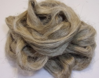 May include: A close-up shot of a pile of raw flax fibers. The fibers are a natural, light tan color, with a slightly coarse texture. The fibers are loosely arranged, creating a swirling pattern. The image is well-lit, highlighting the texture and color of the flax.