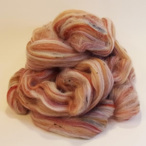 May include: A pile of colorful wool roving in shades of white, pink, orange, and brown. The roving is soft and fluffy, and it is perfect for spinning or felting.