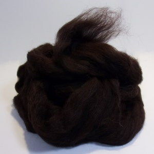May include: A pile of dark brown wool roving, suitable for spinning or felting. The fibers are tightly packed, with some loose strands visible at the top. The wool appears soft and fluffy, ideal for various craft projects.