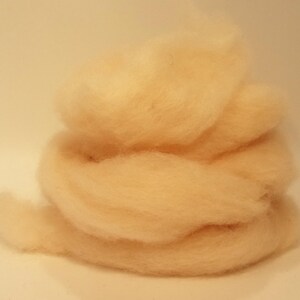 May include: A pile of light peach-colored wool roving.