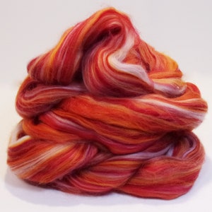 May include: A pile of red, orange, and white wool roving. The roving is arranged in a swirling pattern.