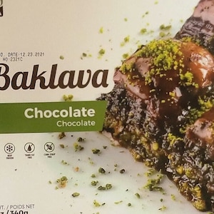 May include: A box of chocolate baklava with a close-up of the pastry topped with pistachios. The box is labeled "Baklava Chocolate Chocolate" and has a net weight of 13 oz / 360g.