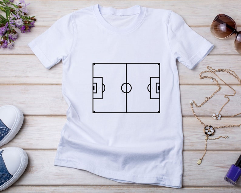 May include: White t-shirt with a black outline of a soccer field printed on the front.
