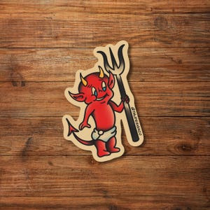 May include: A red cartoon devil with a pitchfork, wearing a diaper and smiling. The devil is holding the pitchfork in its right hand. The image is in a vintage style.