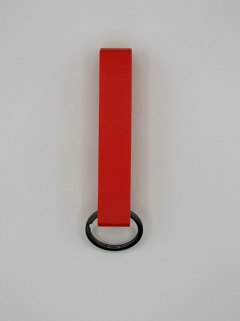 May include: A bright red leather keychain with a black metal ring.