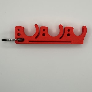 May include: A red plastic keychain with four loops for holding keys. The keychain has a silver key ring attached.